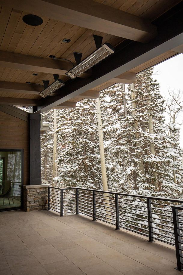 Covered patio with ceiling heaters and snowy forest view