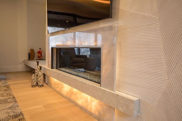 Linear fireplace with glowing marble base and textured wall