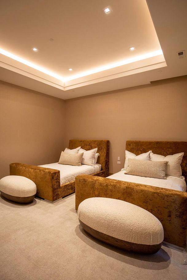 Guest bedroom with twin beds and soft cove lighting