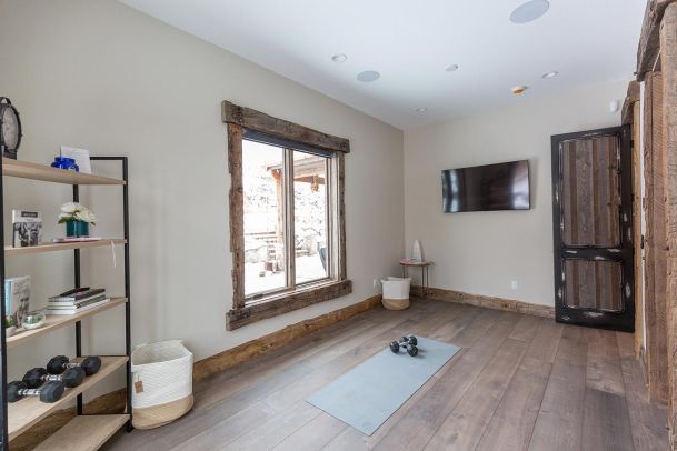 Small yoga room with dumbbells and wall mounted TV