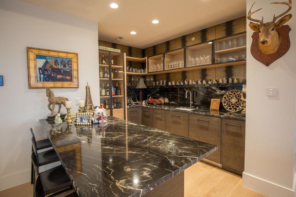 Home bar with black marble counters and deer mount
