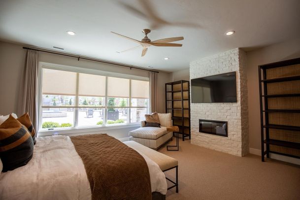Bedroom with motorized shades and white brick fireplace