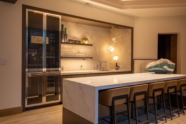 Home bar area with marble backsplash and backlit shelving