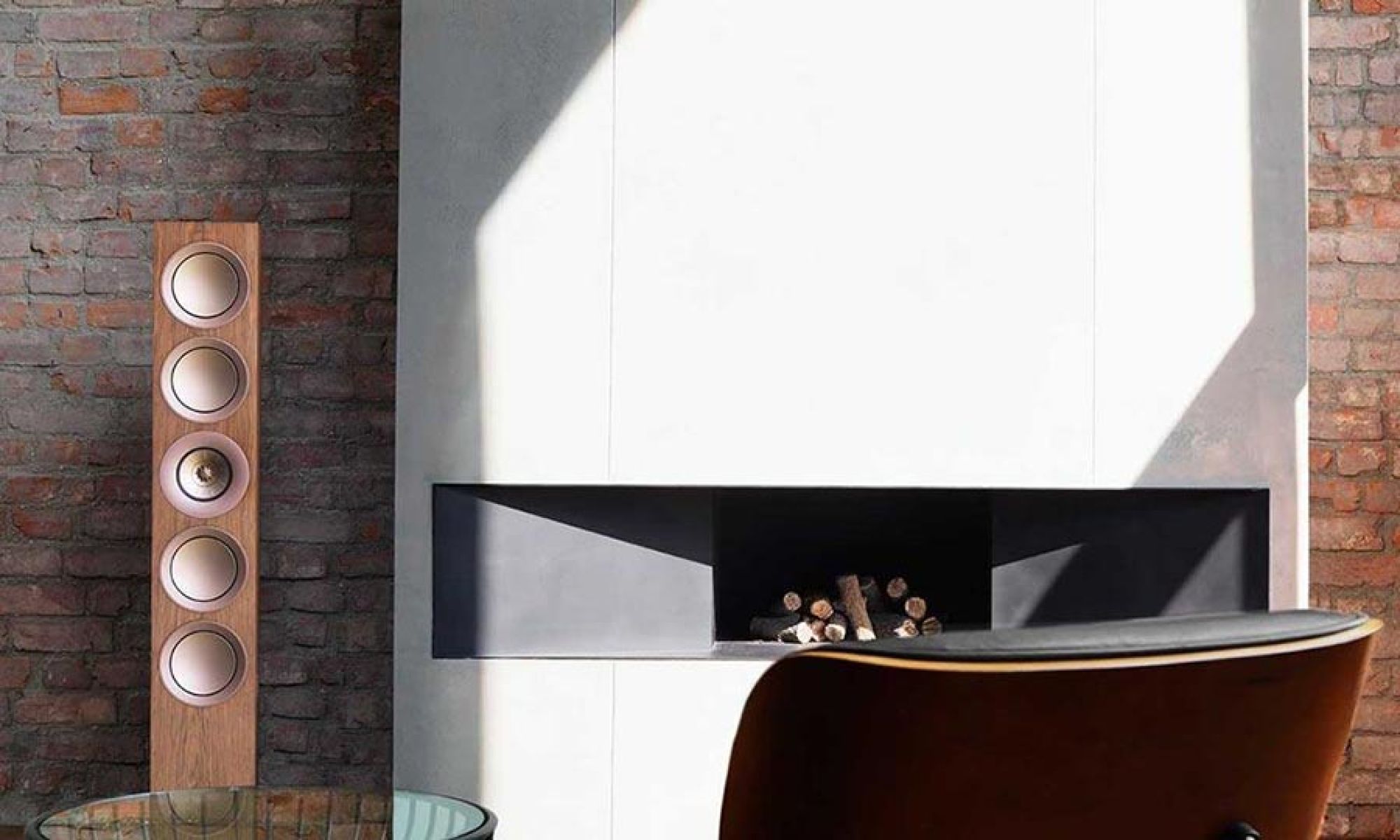 Floorstanding speakers mounted beside a modern fireplace in a minimalist room
