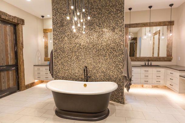 Centered view of a dark soaking tub and mosaic tile wall