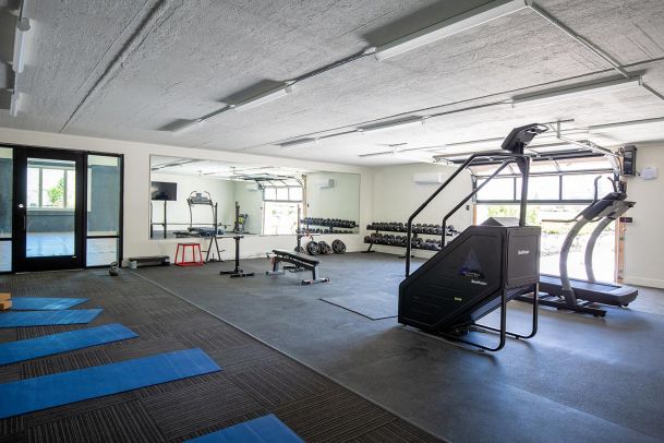 Home gym with mirrored wall and various workout machines